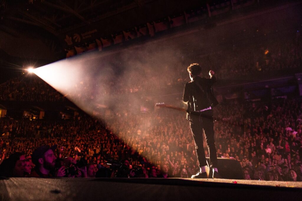 Guitarist performing on stage to a crowd.